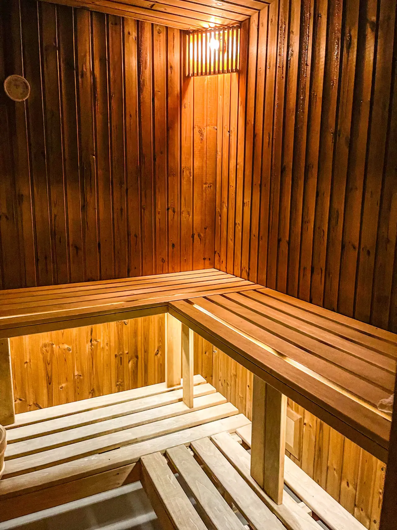 Warm verlichte houten sauna met twee banken